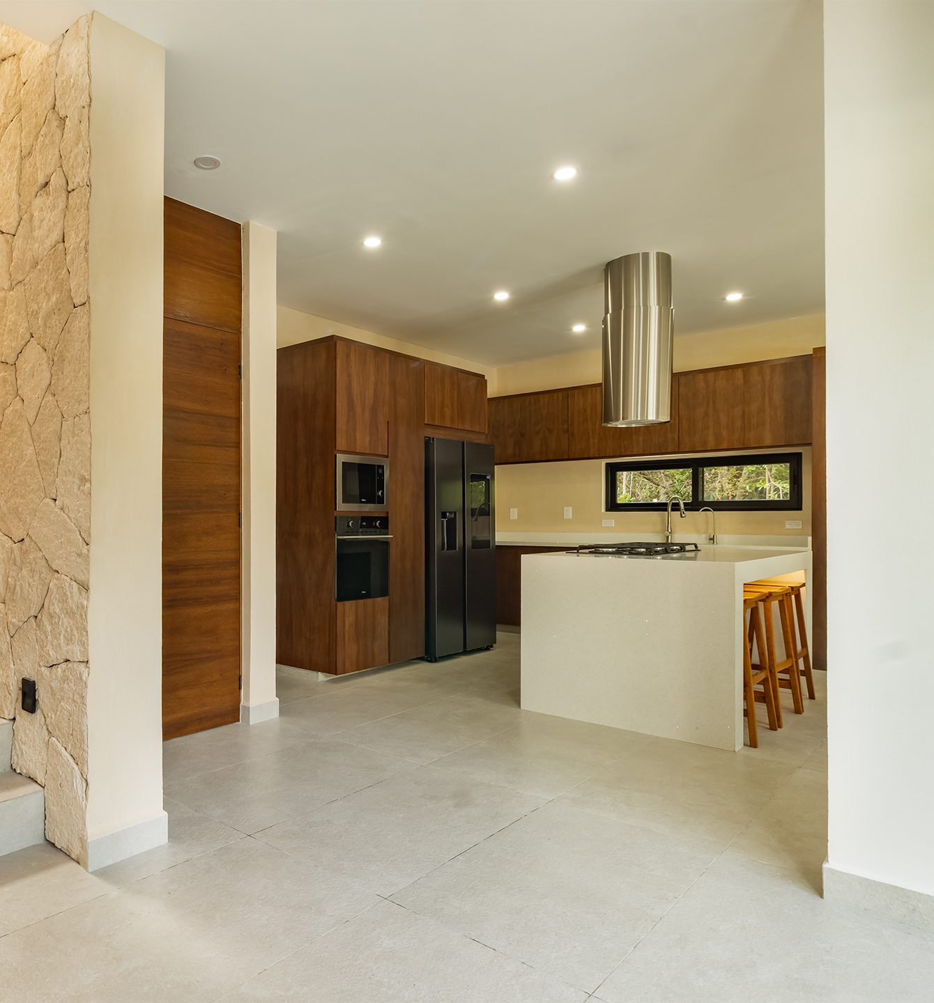 Chef's kitchen viewed past the stone feature wall
